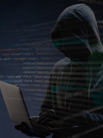 Personne encapuchonnée tapant sur un ordinateur portable, représentant une cyberattaque ou une activité malveillante sur fond de code