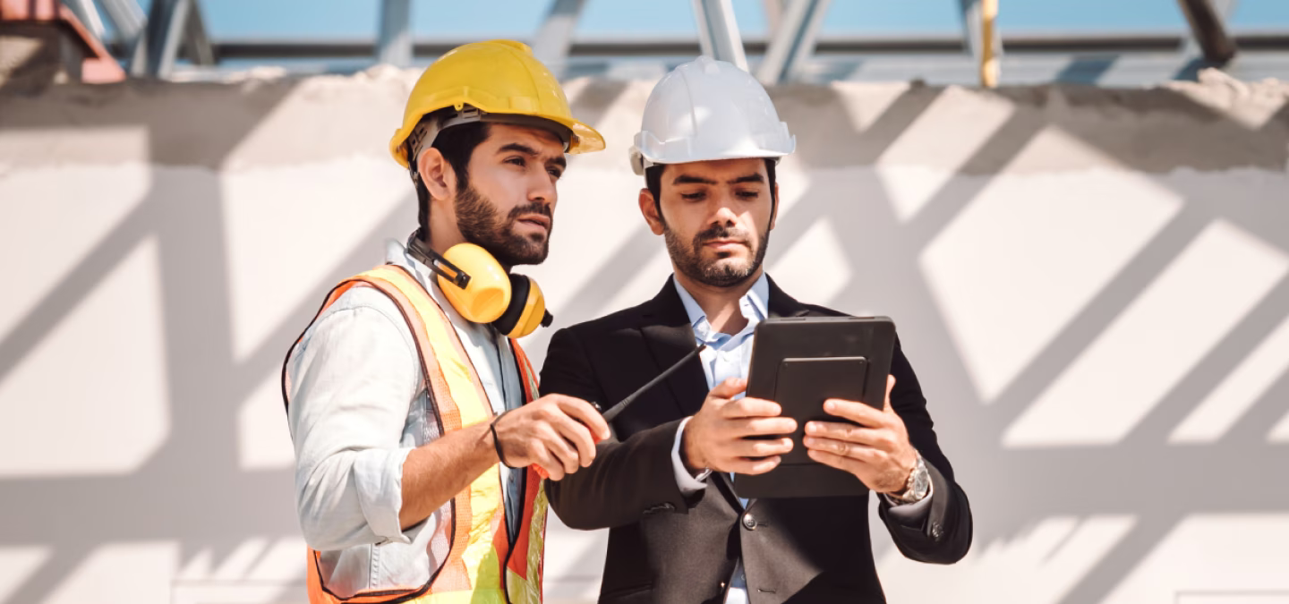 Ingénieur et chef de chantier analysant les plans de construction sur tablette sur un site en travaux