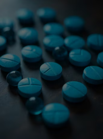 Comprimés et gélules pharmaceutiques bleus sur une table sombre