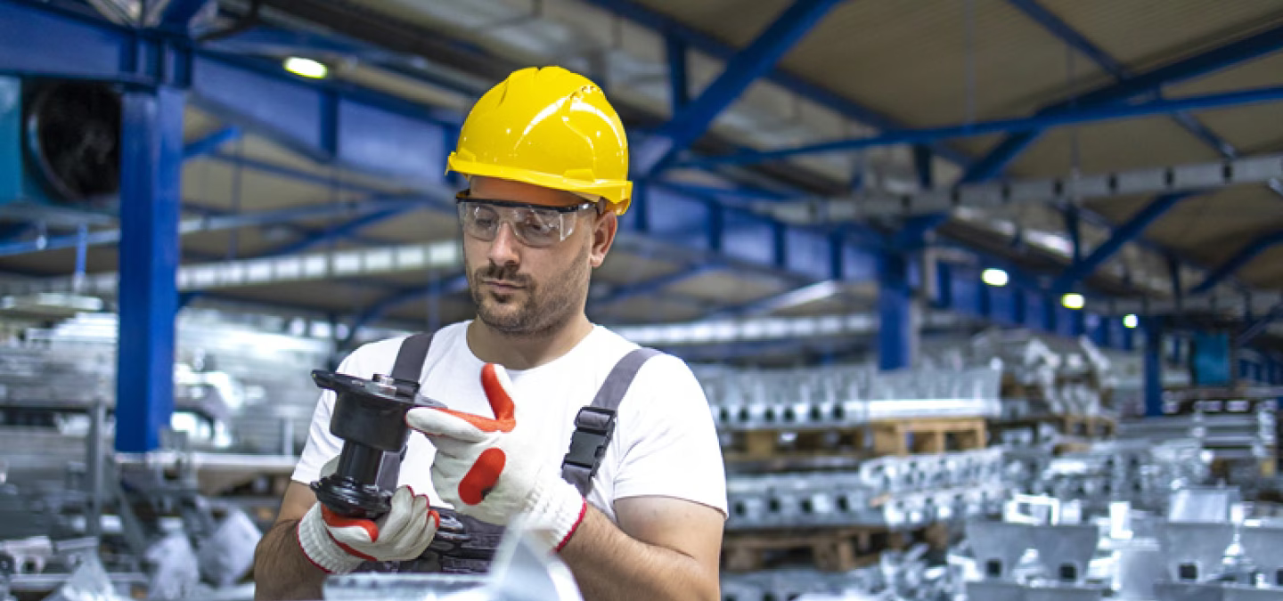 Opérateur industriel inspectant une pièce mécanique dans un atelier de production moderne